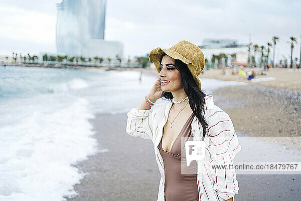 Nachdenkliche Frau mit Sonnenhut am Strand