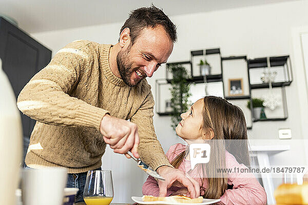 Glücklicher Vater serviert seiner Tochter am Tisch Frühstück