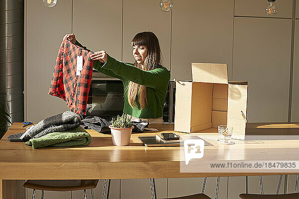 Happy woman checking clothes on table at home