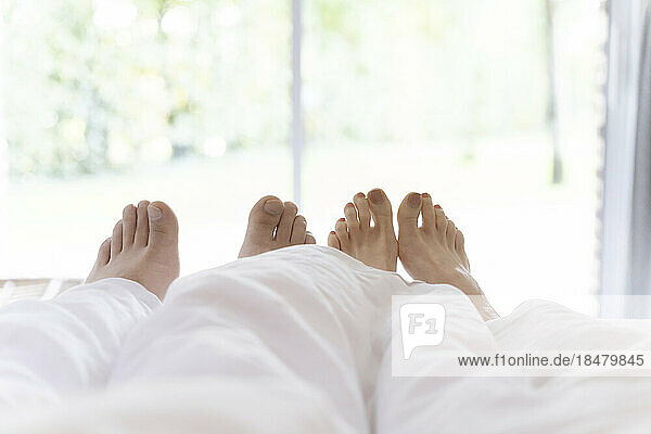 Feet of man and woman under blanket