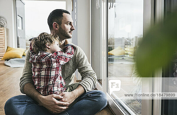 Father and son sitting by glass door at home