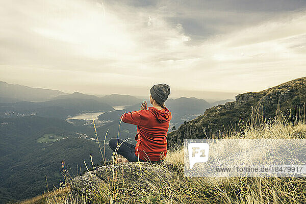 Mature woman meditating with hands clasped on mountain