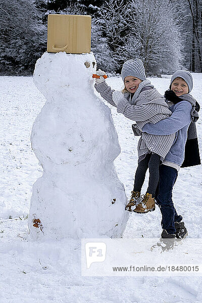 Happy brother and sister making snowman