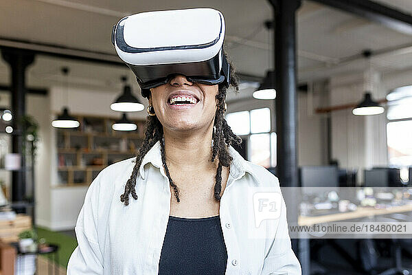 Happy businesswoman with virtual reality simulator in office