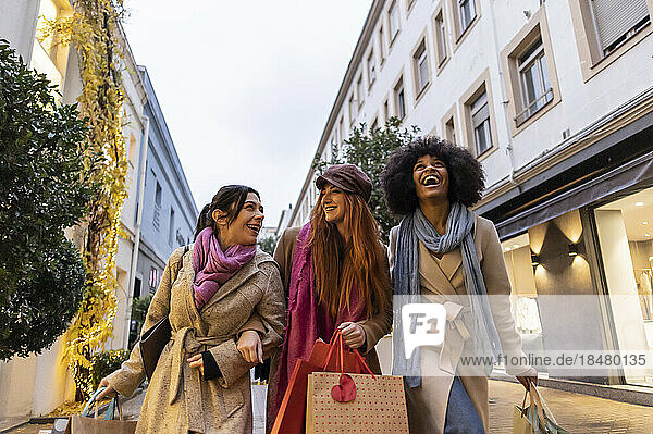 Fröhliche Freunde gehen mit Einkaufstüten spazieren und genießen den Fußweg