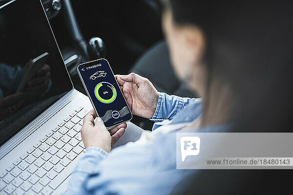 Woman with laptop examining electric car charging app