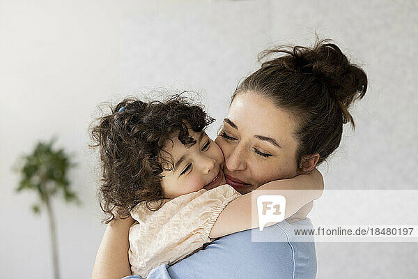 Glückliche Mutter und Tochter umarmen sich mit geschlossenen Augen