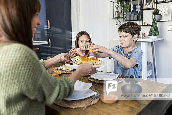 Glückliche Mutter serviert Kindern am Tisch Frühstück