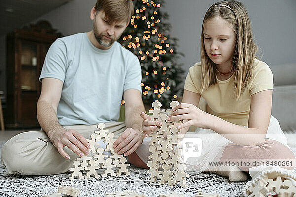 Vater und Tochter spielen zu Weihnachten zu Hause mit Holzspielzeug