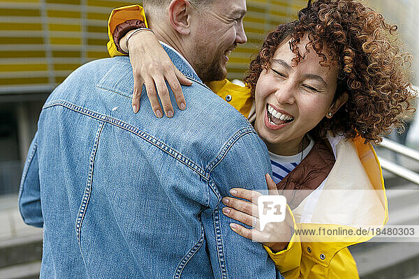 Happy woman with curly hair embracing man