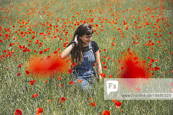 Young woman amidst poppy flowers on sunny day