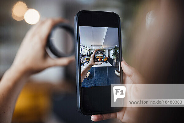 Hands of businesswoman photographing circular equipment through smart phone in office