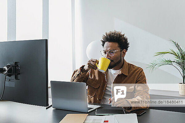 Businessman drinking coffee and working in office
