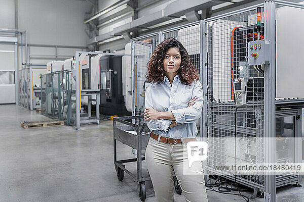Smiling engineer with arms crossed standing in front of machine