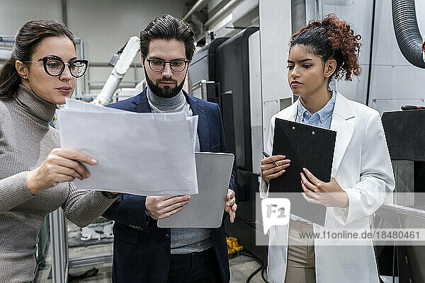 Businesswoman discussing over document with colleagues in industry