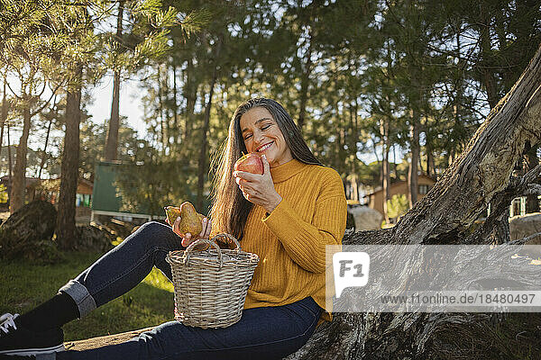Smiling mature woman holding an apple in nature