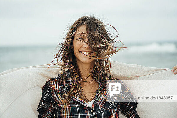 Glückliche Frau mit zerzausten Haaren am Strand