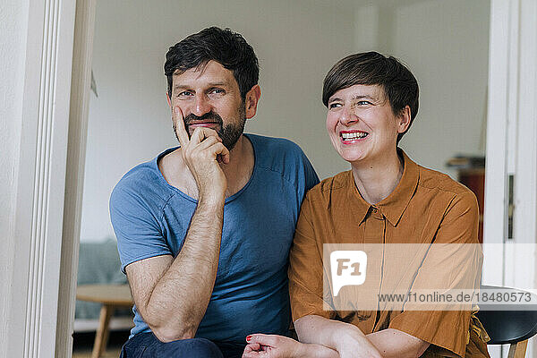Smiling man with hand on chin by woman at home