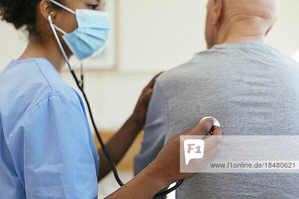 Doctor using stethoscope for listening to patient's heartbeat at home