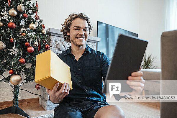 Happy man with box talking on video call through tablet PC