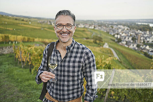Happy mature man with wineglass on hill