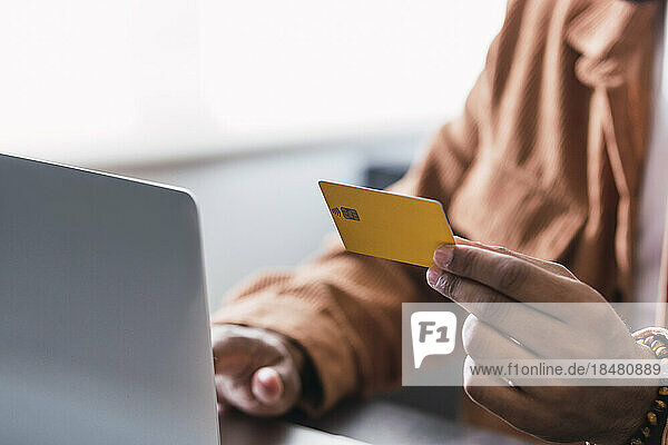 Hand eines Geschäftsmannes mit Kreditkarte und Laptop am Schreibtisch