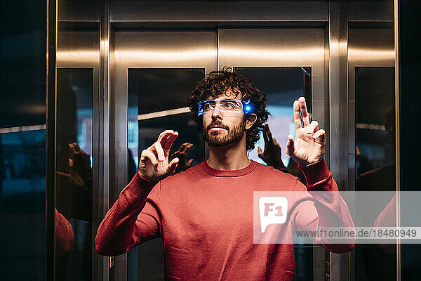 Man wearing smart eyeglasses gesturing in elevator