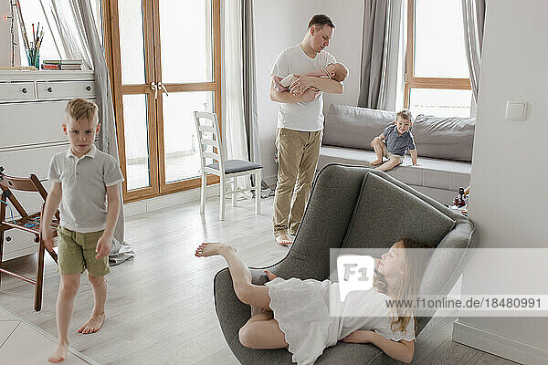 Vater trägt Jungen mit Kindern  die zu Hause spielen