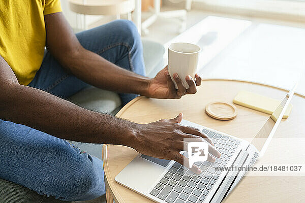 Freelancer with coffee cup working on laptop at home