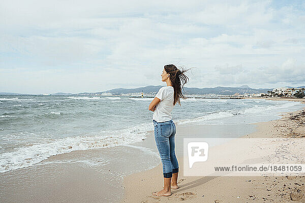 Frau steht auf Sand in Ufernähe am Strand