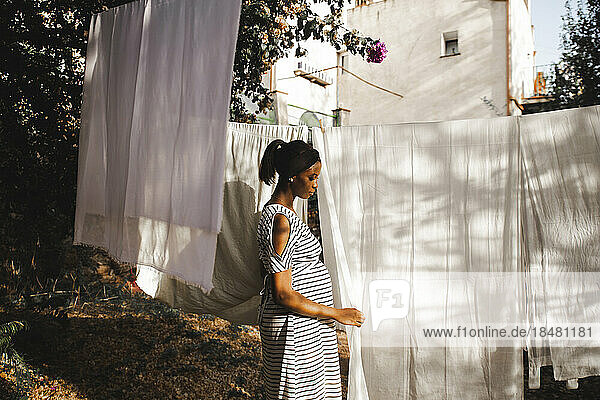 Pregnant woman hanging white sheet in backyard
