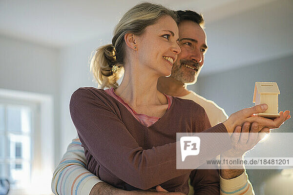 Smiling mature couple holding house model