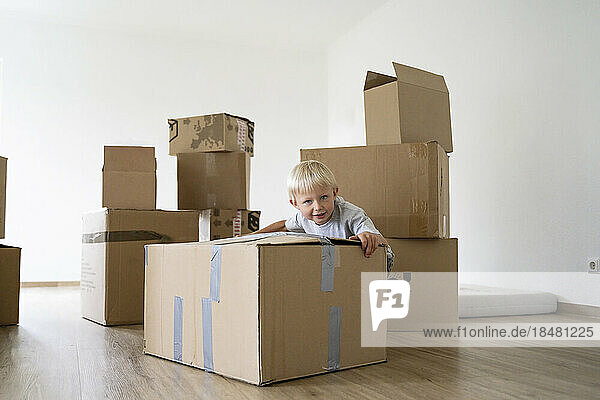Little boy pushing cardboard box at home