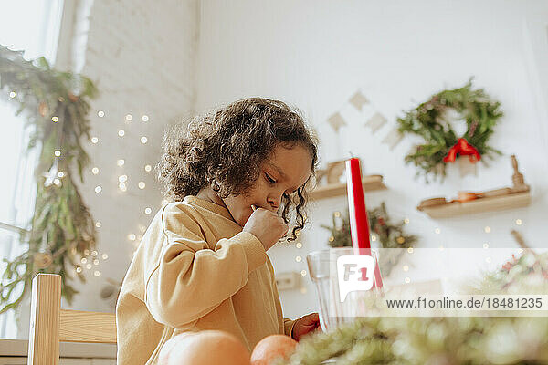 Cute girl eating cookies in kitchen at Christmas