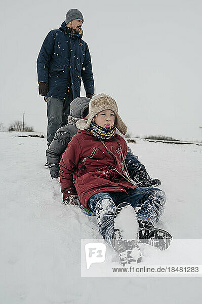 Vater und verspielter Sohn sitzen im Schnee