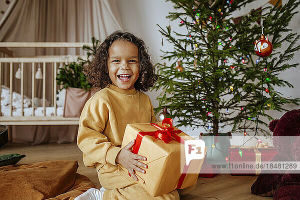 Glückliches Mädchen  das zu Hause Geschenke unter dem Weihnachtsbaum öffnet