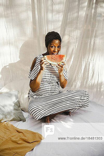 Schwangere Frau isst frische Wassermelone im Hinterhof