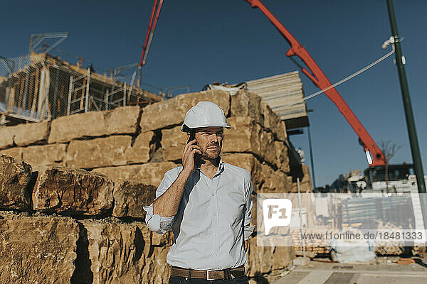 Mature architect talking on smart phone in construction area