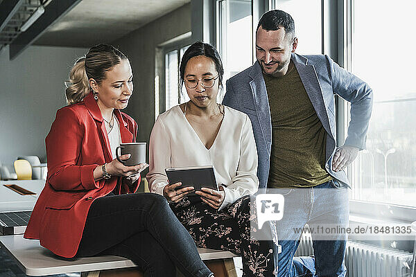 Gemischtrassige Geschäftskollegen schauen sich bei einer Besprechung im Büro einen Tablet-PC an