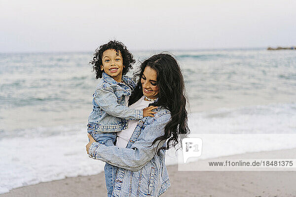 Mother and son wearing denim jackets at beach