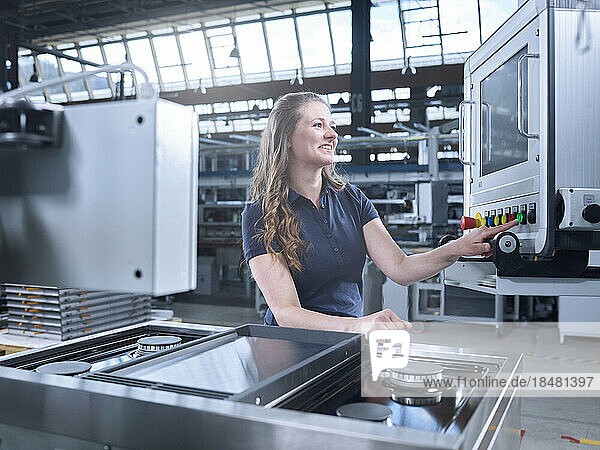 Smiling engineer operating modern machines at factory