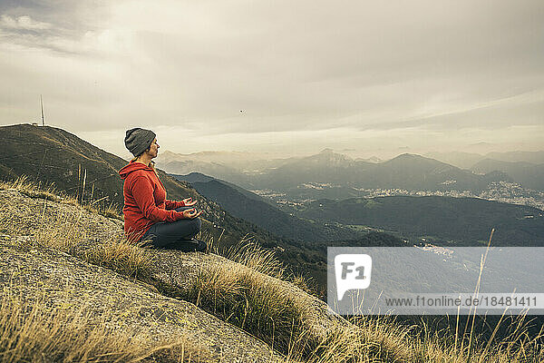 Mature woman meditating on mountain
