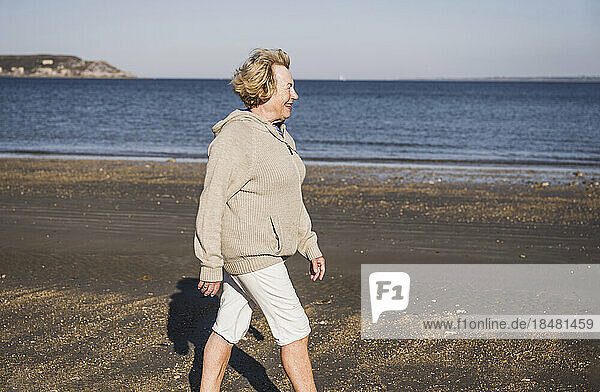 Smiling elderly woman walking by sea at beach