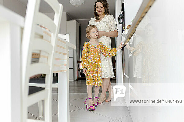 Girl wearing mother's shoes in kitchen at home