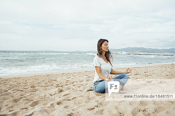 Woman doing yoga sitting on sand at beach