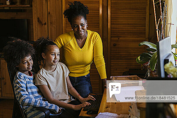 Smiling woman with son and daughter using computer at home