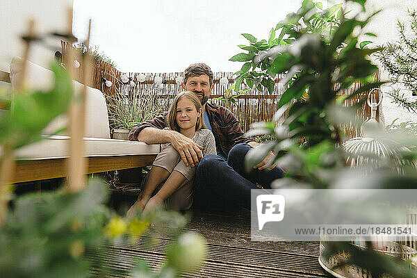 Lächelnder reifer Mann sitzt mit Tochter auf dem Balkon