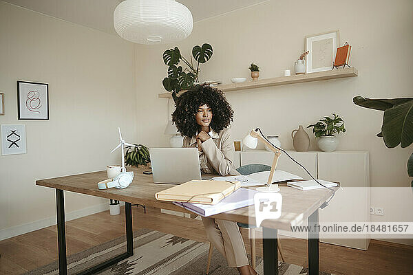 Nachdenkliche Geschäftsfrau sitzt mit Laptop am Schreibtisch im Büro