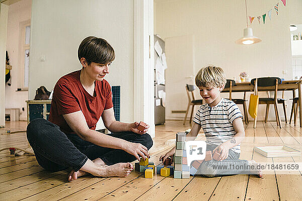 Mother and son playing with toy blocks sitting at home