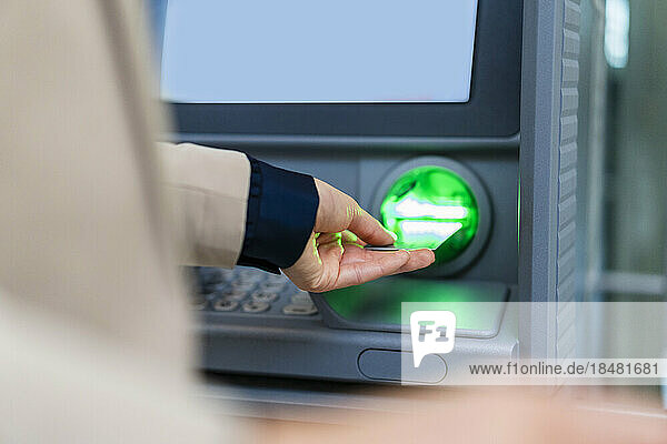 Hand of businesswoman inserting credit card in ATM